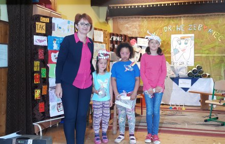 Dzieci z panią nauczyciel na tle prac plastycznych