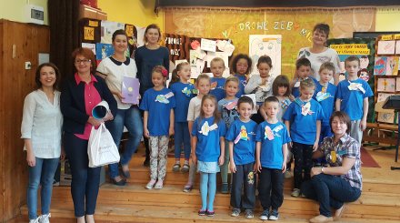 Dzieci z panią nauczyciel na tle prac plastycznych