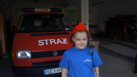 Jeden z uczniów w hełmie strażackim