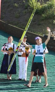 Andreas Wellinger z uniesionymi rękami świętuje zajęcie 3. miejsca