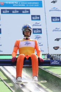 Maciej Kot w żółtym plastronie lidera FIS Grand Prix na belce startowej