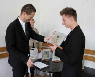 Łukasz Podżorski odbiera statuetkę z rąk przewodniczącego rady Miasta