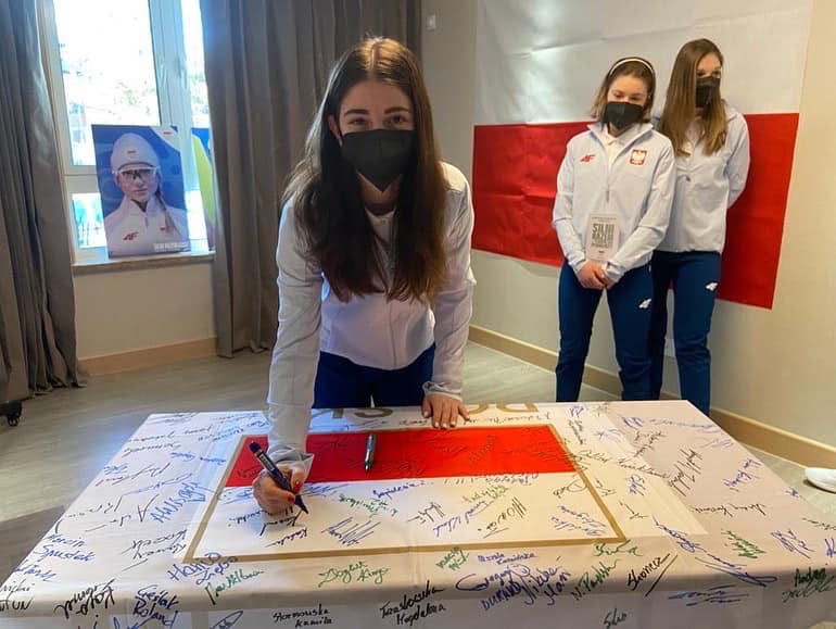 Nikola Konderla składa podpis na pamiątkowej fladze