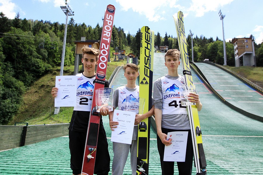 Najlepsi skoczkowie na podium na tle skoczni w Szszyrku